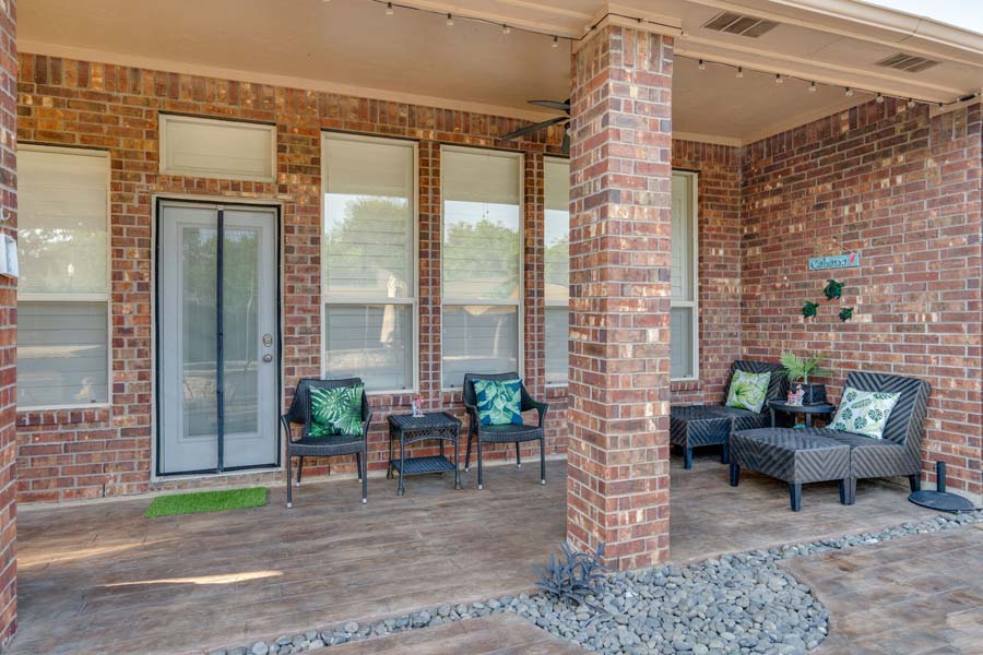 Weekly Pool Cleaning Service by Flower Mound Pool Care and Maintenance. Image of back of house with doors and chairs around the entry to the deck and pool area.