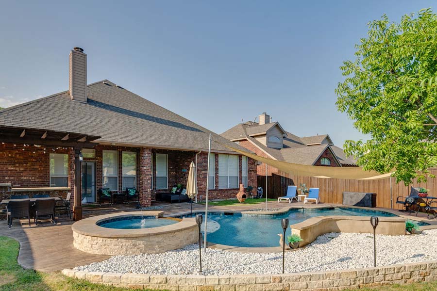 Weekly Pool Cleaning Service by Flower Mound Pool Care and Maintenance. Image of whole pool area in back of house.