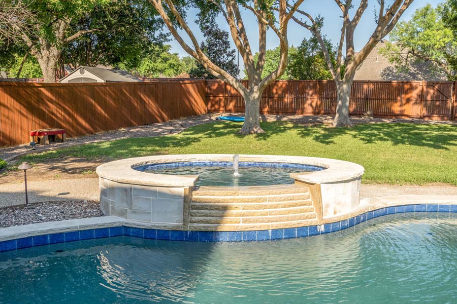 Weekly Pool Cleaning Service by Flower Mound Pool Care and Maintenance. Image of a jacuzzi in the foreground taken from a front angle in back of house. Image from a different angle.