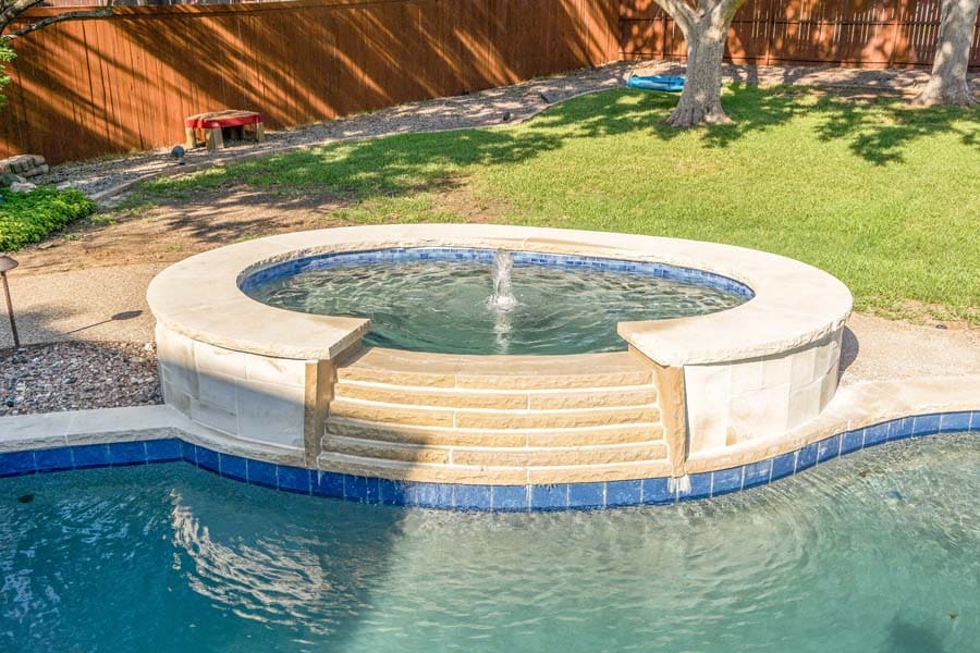 Weekly Pool Cleaning Service by Flower Mound Pool Care and Maintenance. Image of a jacuzzi in the foreground taken from a front angle in back of house.